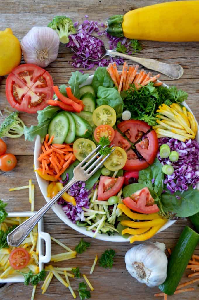 Colorful salad as a side dish for bbq with greens, red and yellow tomatoes, orange carrots, purple cabbage.