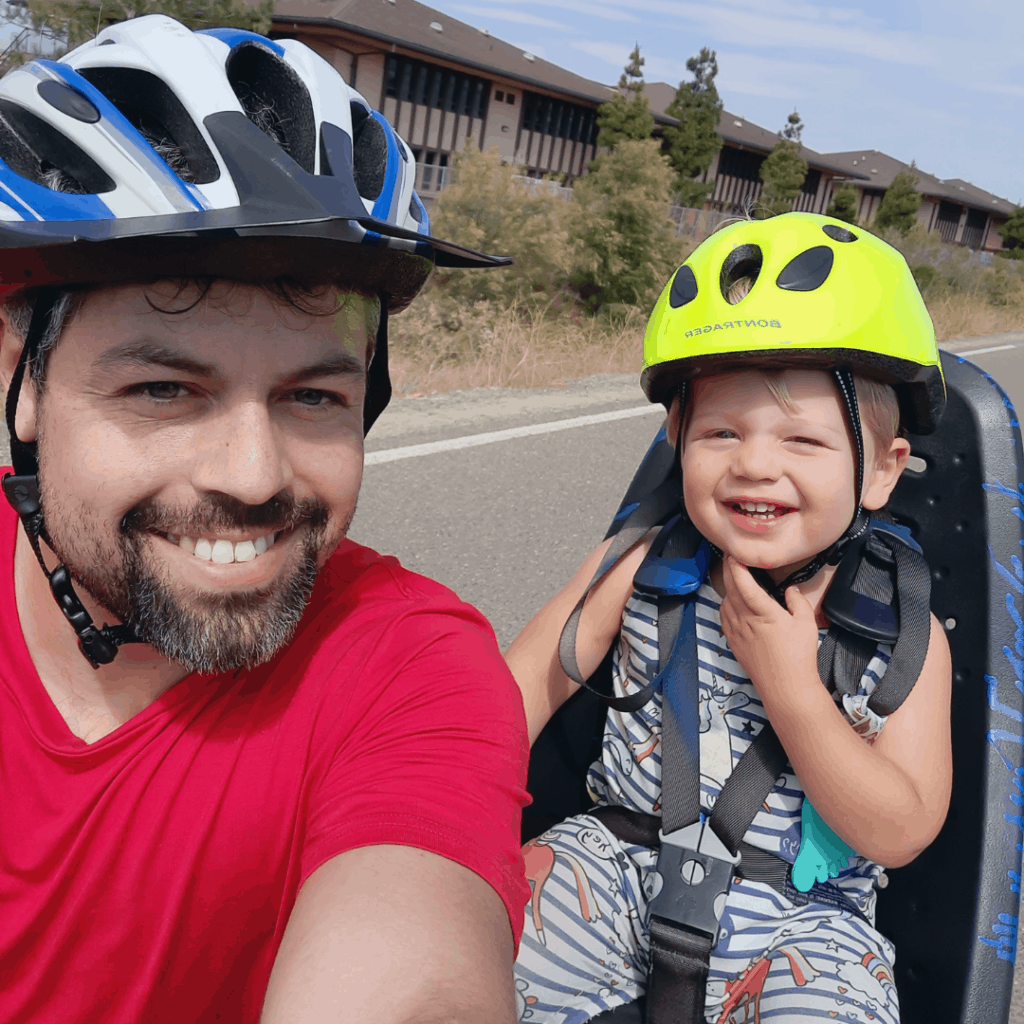 Man and small child smiling. Bike riding on a sunny day, enjoying some of the best active recovery workouts together.