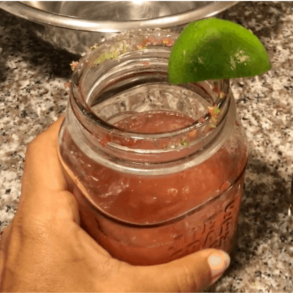 Mason jar with an easy recipe for a margarita with fresh strawberries and jalapeno.