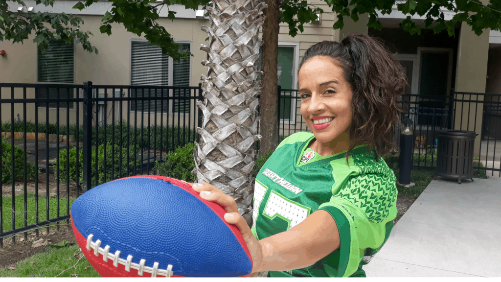Woman in team jersey holding football for a quick workout before the enjoying food for game day