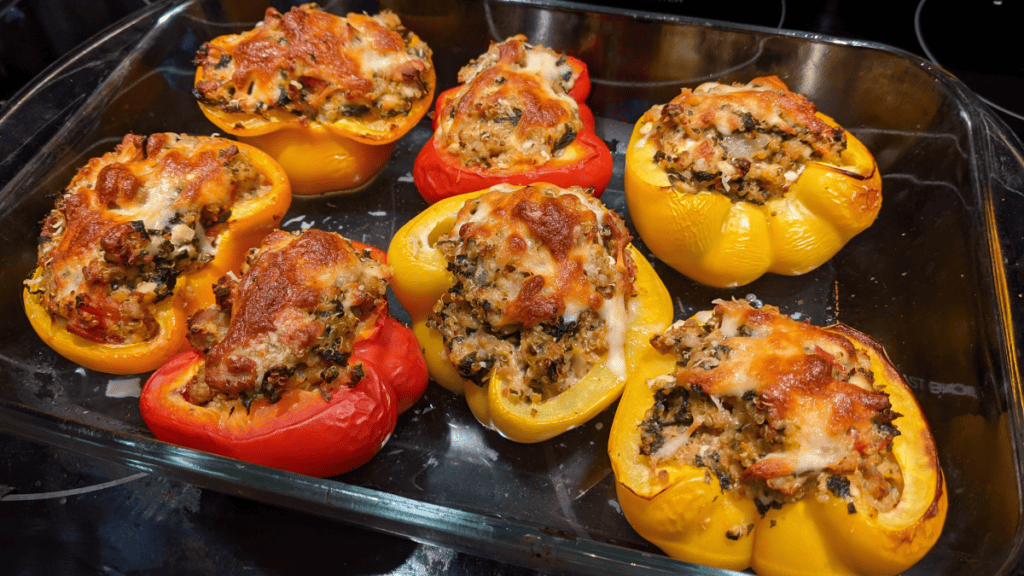 Red and yellow stuffed quinoa bell peppers made into a saucy lasagna, cooked and ready to pull out of the oven.