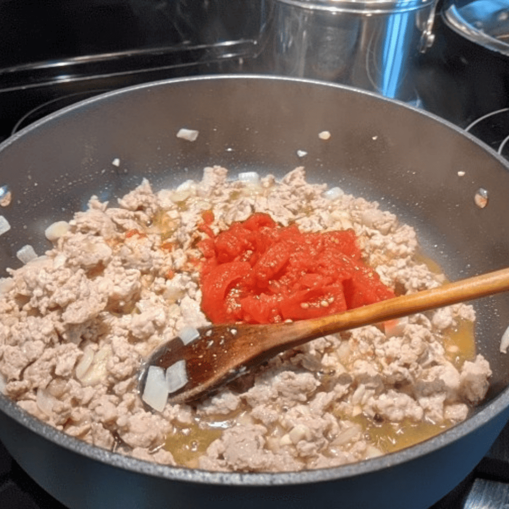Cooking a protein-rich filling for saucy Bell pepper lasagna with ground chicken.