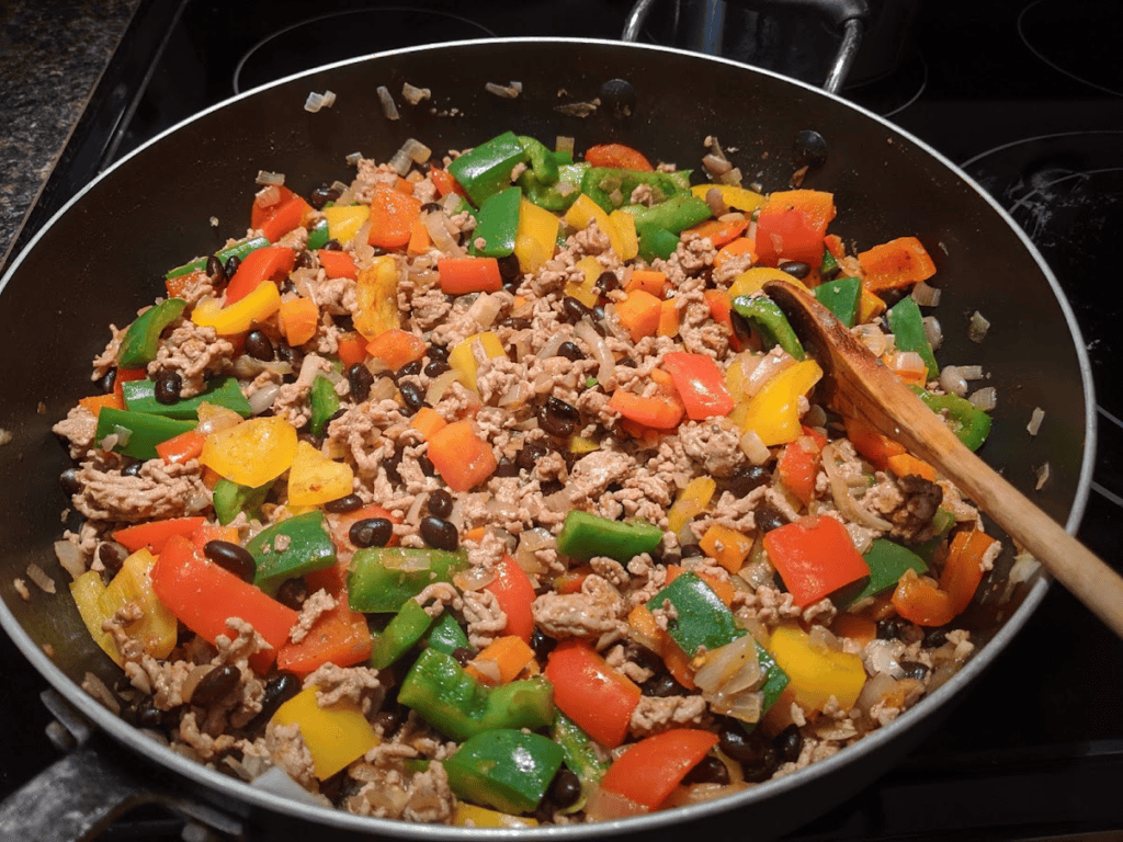 Lean ground beef and tricolor bell peppers cooking for taco bar ingredients