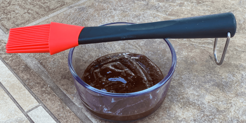 Kansas City style BBQ sauce recipe with molasses ready to be applied with a basting brush.