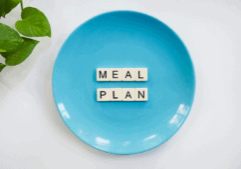 Light blue plate on a white background with the letters meal plan, shown at the top of an article for dinner meal planning for healthier eating.