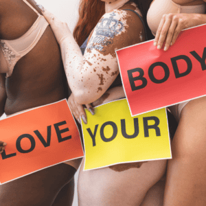 Women who feel good in their own skin, featuring their “imperfections” and “insecurities,” holding signs that read Love Your Body